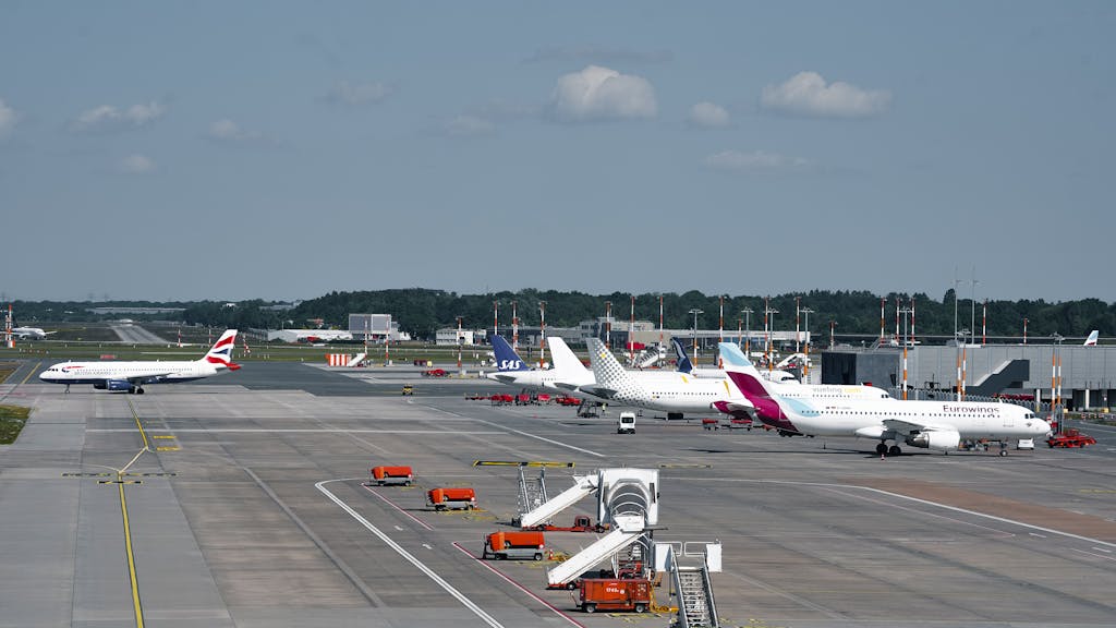 Airplanes on the runway at Hamburg Airport on a clear day, showcasing bustling air travel.