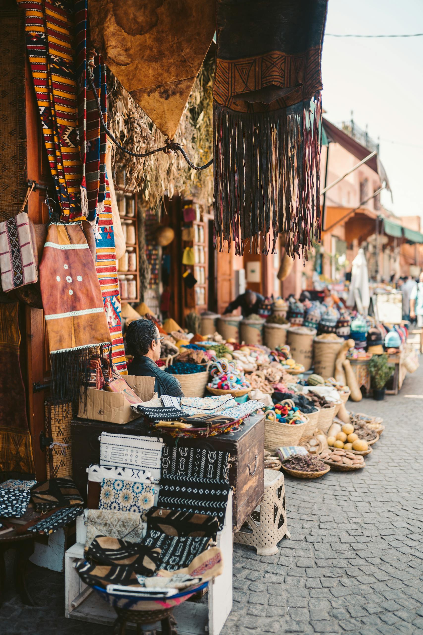 Colorful street market in Marrakesh, Morocco showcasing textiles and handmade crafts.